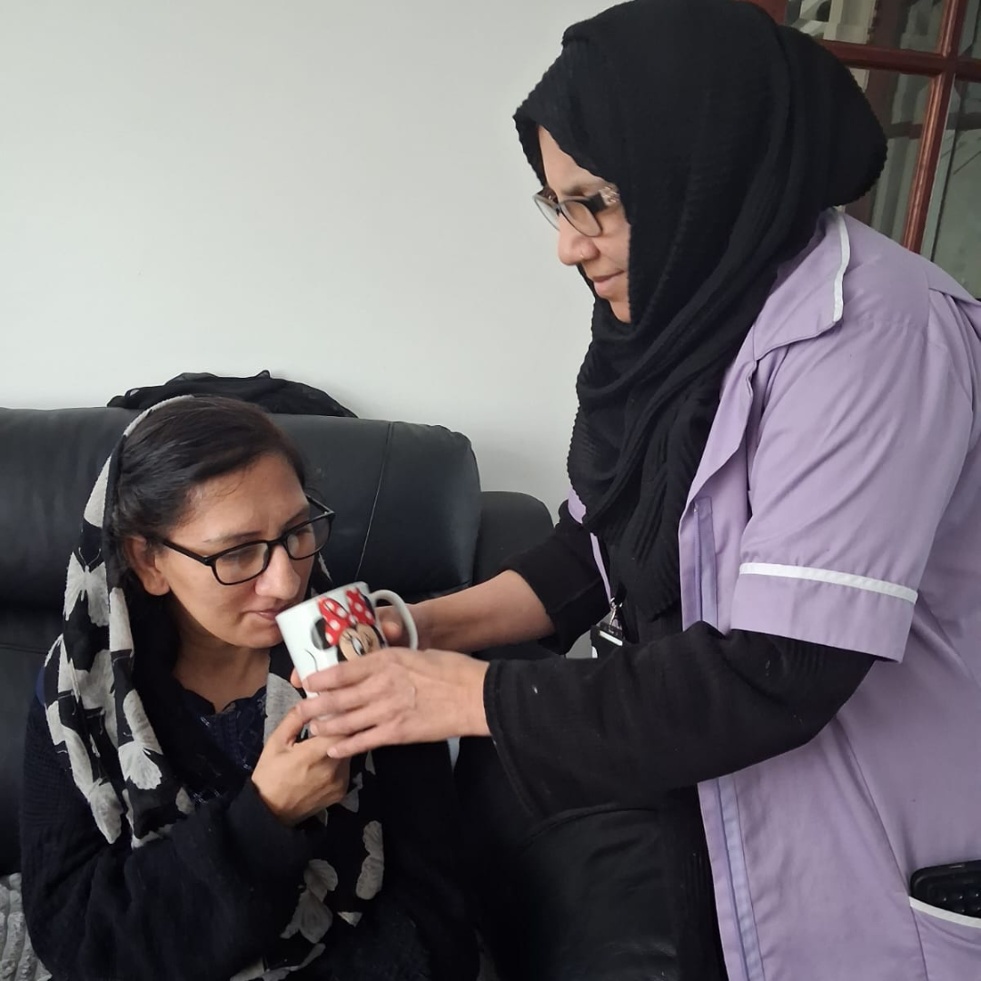Thumhara assistant helping asian lady drink from mug