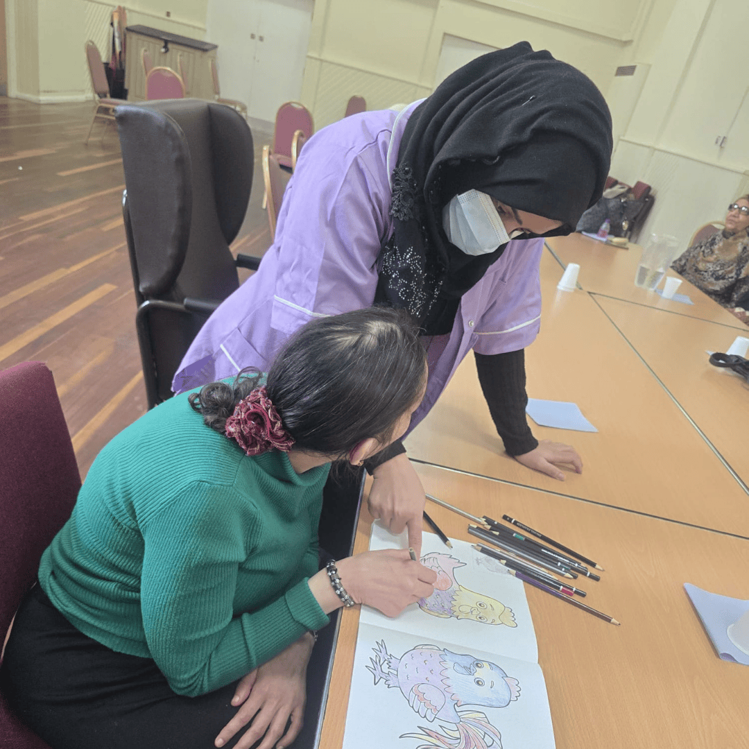 Thumhara volunteer helping with colouring exercise
